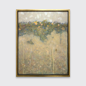 A muted yellow, green and beige abstract landscape print in a gold floater frame hangs on a white wall.