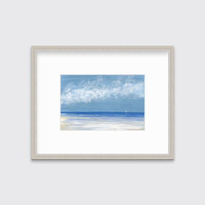 A blue, white and light blue abstract seascape in a silver frame with a mat hangs on a white wall.