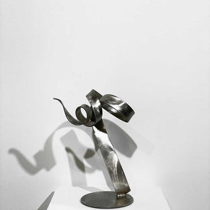 Stainless steel, abstract sculpture, from the front view, sitting on a pedestal in front of a white wall.