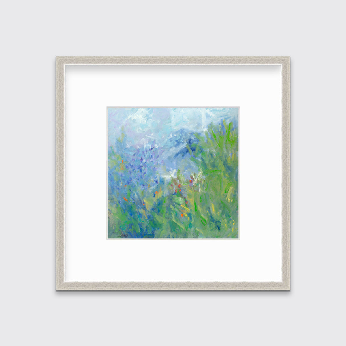 A blue, green, yellow and white abstract floral print in a silver frame with a mat hangs on a white wall.
