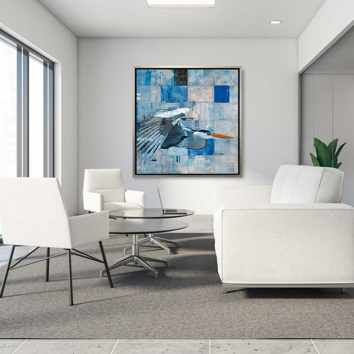 A blue abstract print of a blue heron in a silver floater frame hangs on a white wall across from a white sofa, two white chairs and two low round desks.