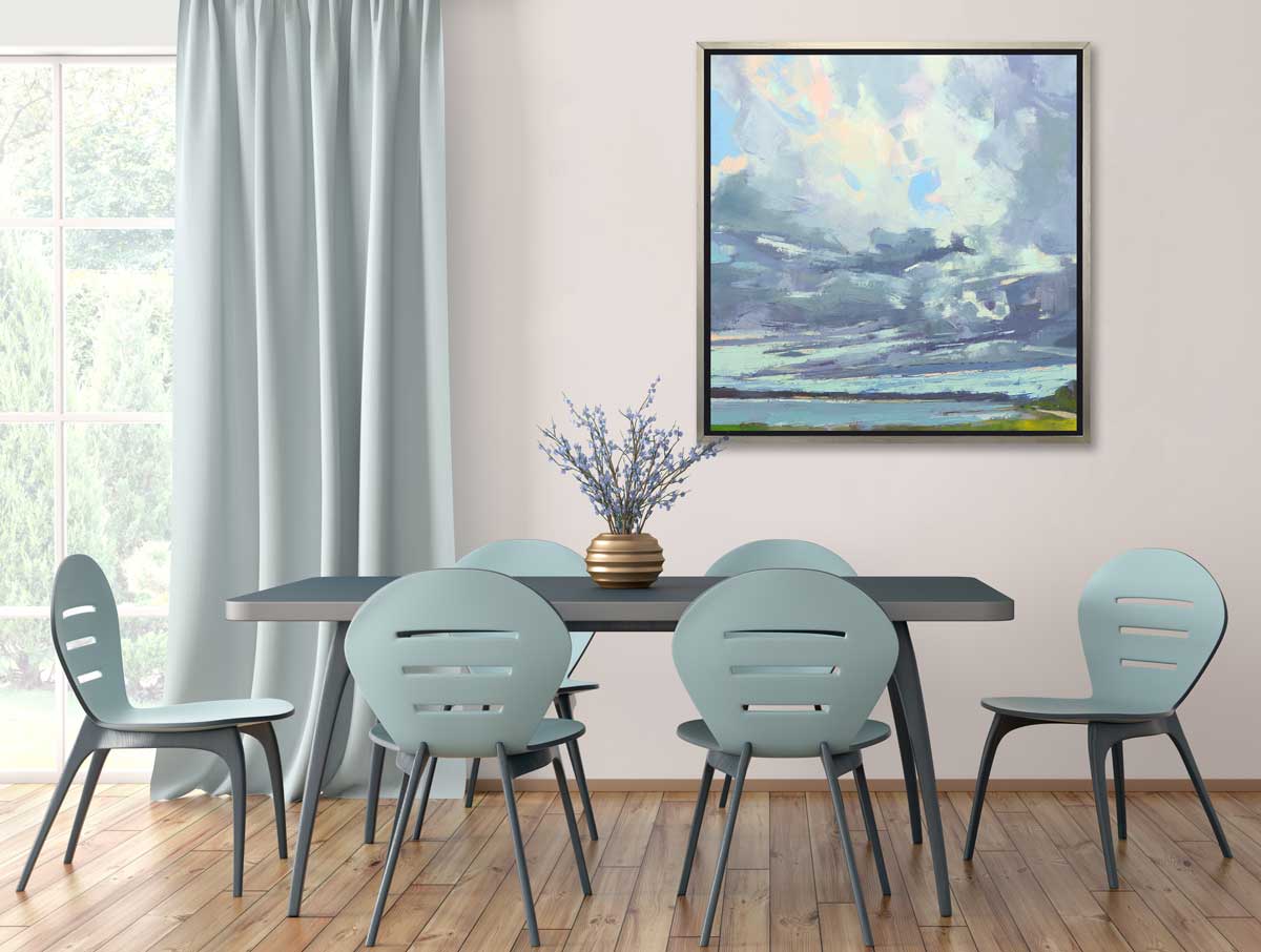 A blue, white and green abstract landscape print in a silver floater frame hangs on a white wall above a dark teal table with a purple floral stem arrangement in a round gold vase, six light teal chairs surround the table.