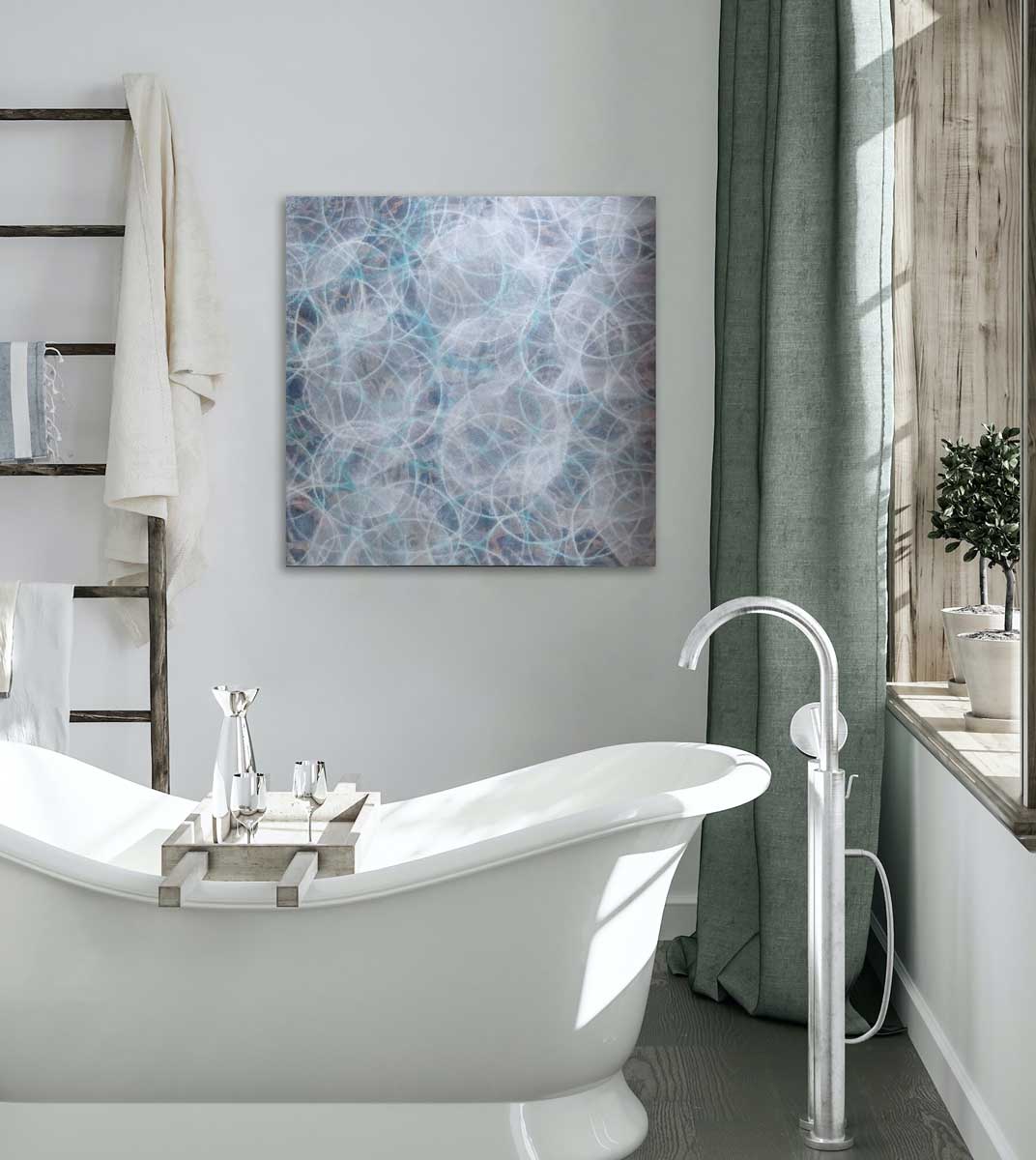 A blue, white and teal overlapping circles painting hangs on a white wall above a deep soaking white bathtub.