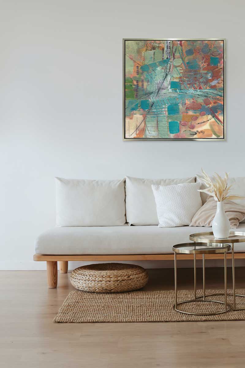 A Linda Bigness print in a sliver floater frame hangs over a white couch, on a white wall.