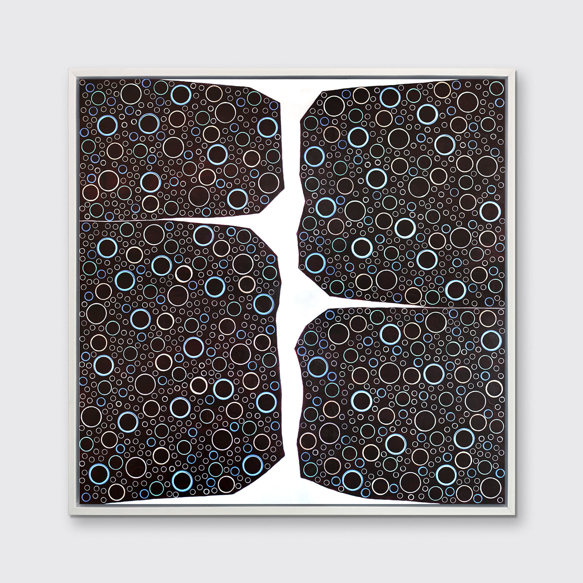 A multicolored abstract print in a white floater frame hangs on a white wall.