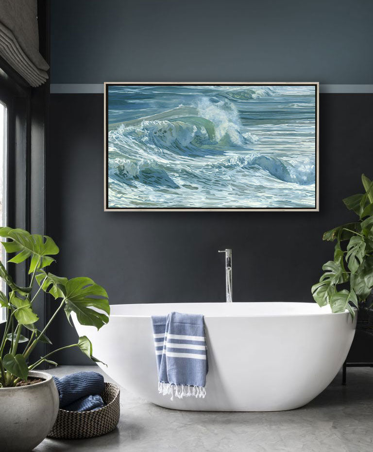 Rolling waves on a side angle with tones of blue, green and white staged in a silver floater frame on a dark charcoal wall above a high sided tub