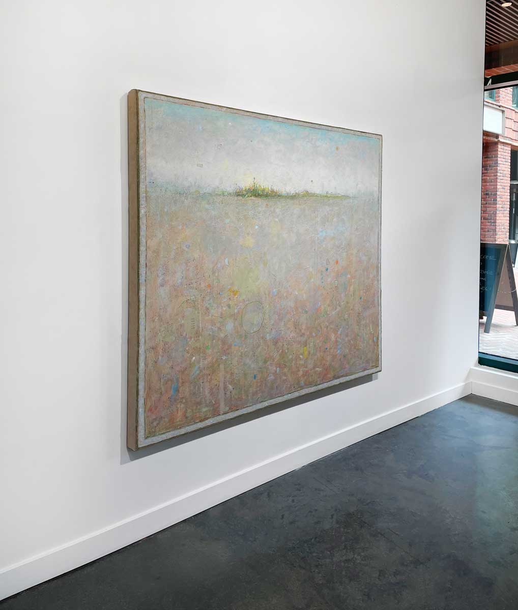 A left side-angle view of a peach colored abstract landscape by Elwood Howell hangs on a white wall.