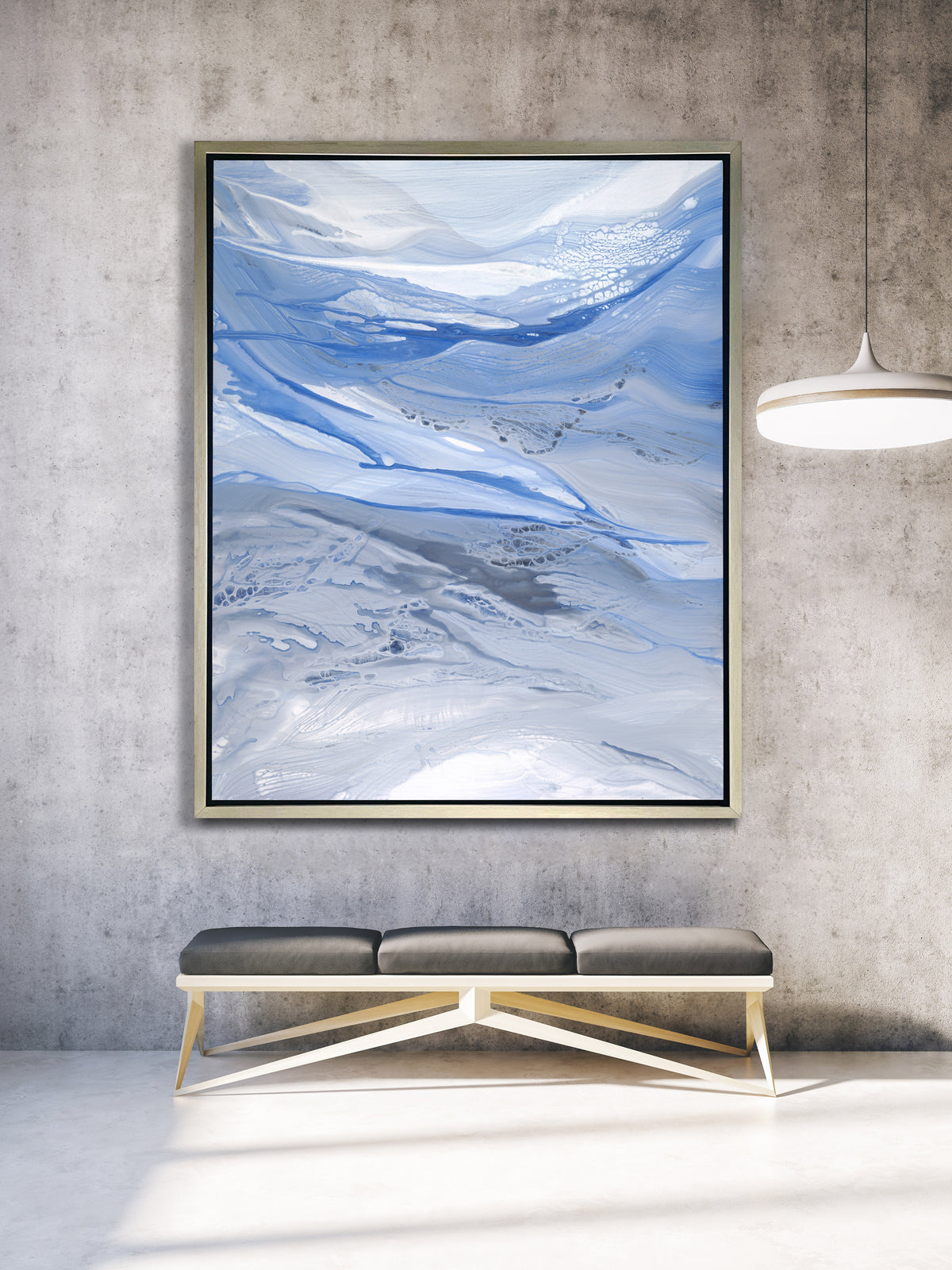 A blue, white and grey abstract print in a silver floater frame hangs on a concrete grey wall above a grey and white bench.