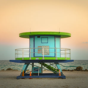 A rear view photograph of a turquoise and lime green cylinder shaped lifeguard stand in Miami, Florida.
