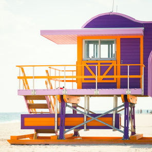 A side view photograph of a purple, orange, and lavender lifeguard stand in Miami, Florida.