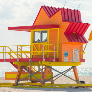 A side view photograph of a orange, yellow, and red lifeguard stand in Miami, Florida. 
