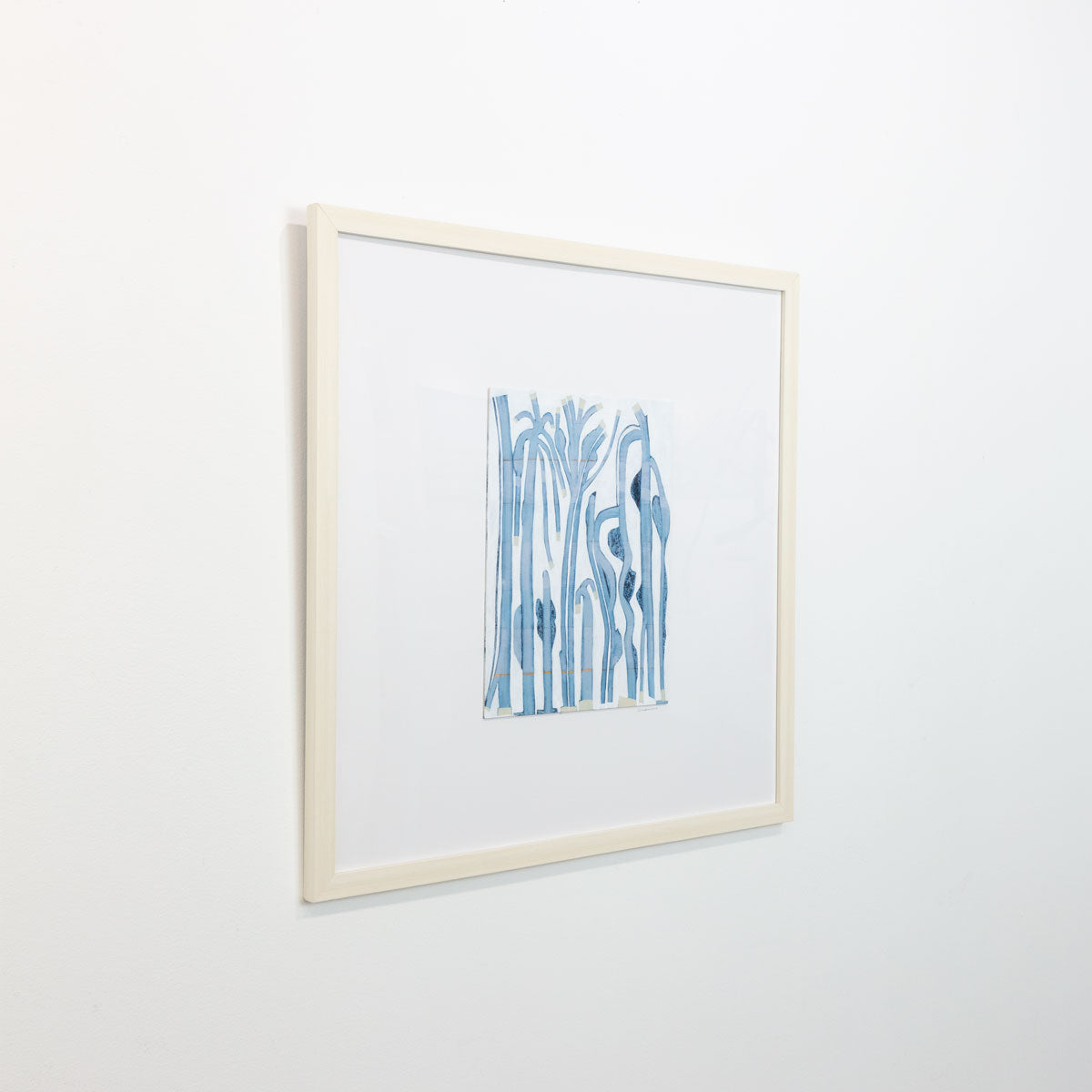 An abstract painting of blue and beige tree-like forms is seen at an angle on a gallery wall.