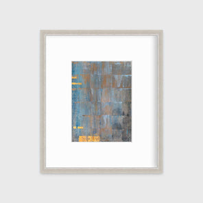 A blue, grey and gold abstract geometric print in a silver frame with a mat hangs on a white wall.