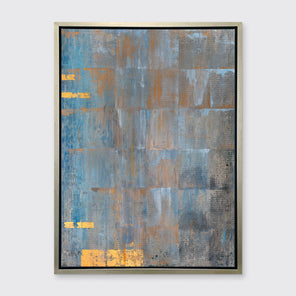 A blue, grey and gold abstract geometric print in a silver floater frame hangs on a white wall.