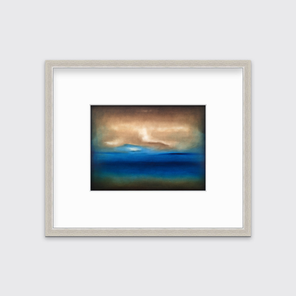 A dark brown, blue, white and teal abstract landscape print in a silver frame with a mat hangs on a white wall.