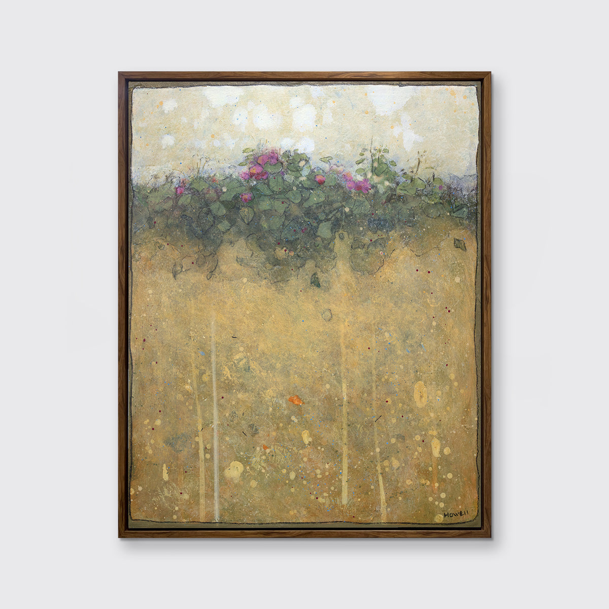 A dark yellow, green and beige abstract landscape print in an oak wood floater frame hangs on a white wall.