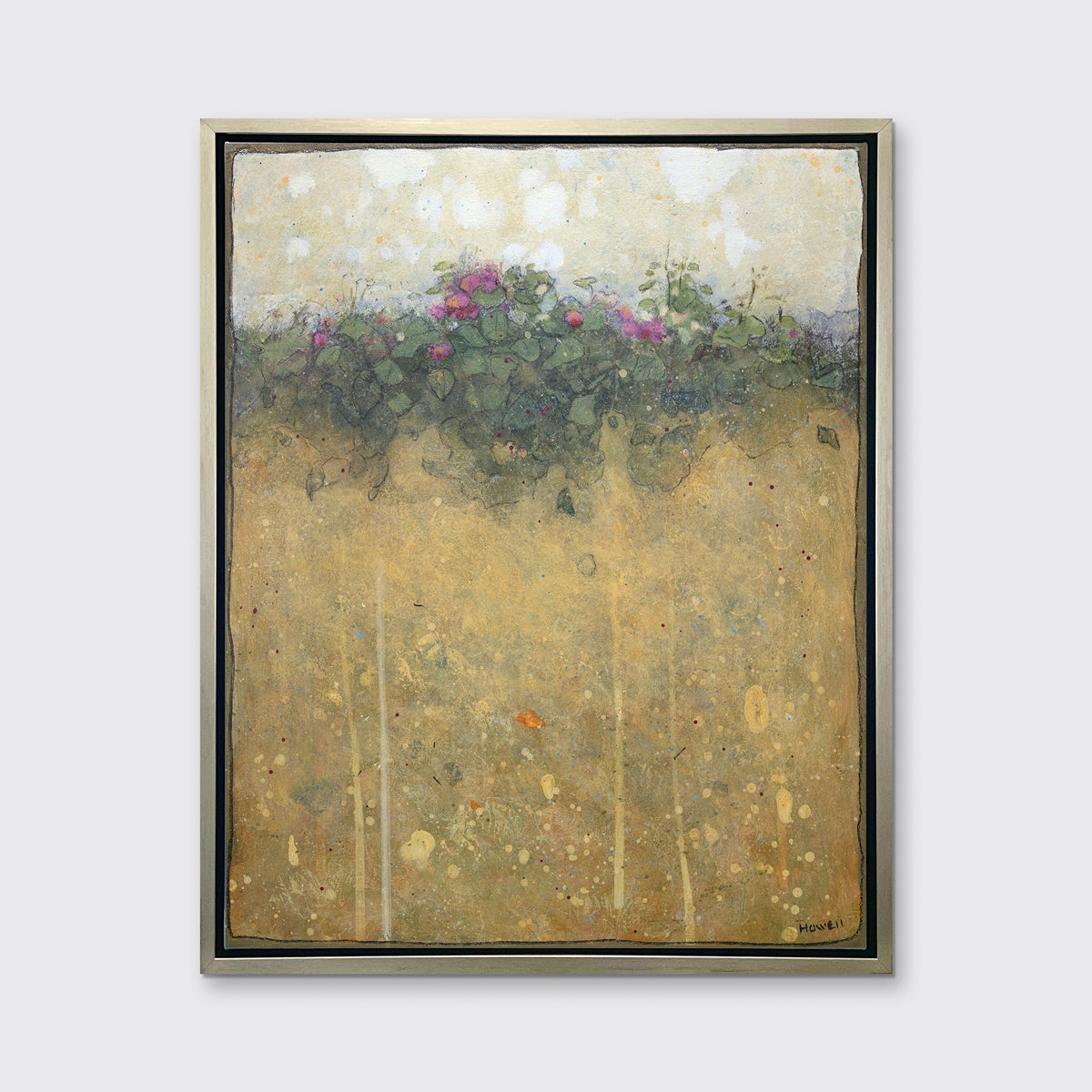 A dark yellow, green and beige abstract landscape print in a silver floater frame hangs on a white wall.