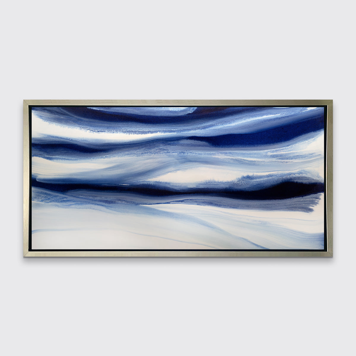 A dark blue and white abstract print in a silver floater frame hangs on a white wall.