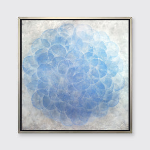 A blue, white and silver abstract geometric print in a silver floater frame hangs on a white wall.