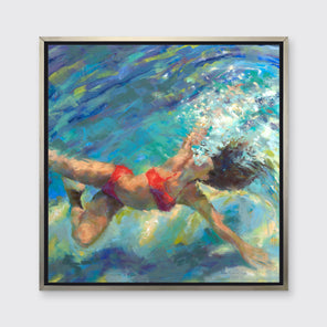 An abstract figurative of a woman in a red bikini underwater in a silver floater frame hangs on a white wall.