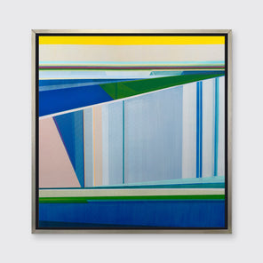 A blue, green and yellow geometric abstract print in a silver floater frame hangs on a white wall.