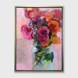 A pink, orange and green abstract floral print in a silver floater frame hangs on a white wall.