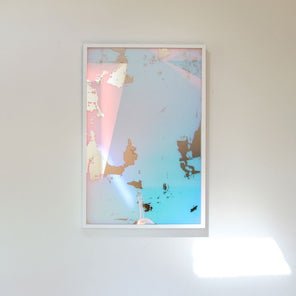 An art mirror with dichroic film by Alina B hangs on a white wall.