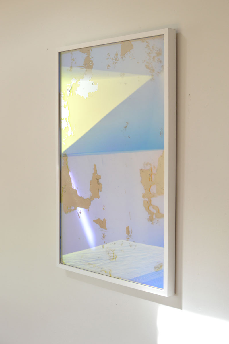A right side-angle view of an art mirror by Alina B hangs on a white wall.