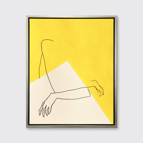 A yellow and white abstract print by Hazal Ozturk in a silver floater frame hangs on a white wall.