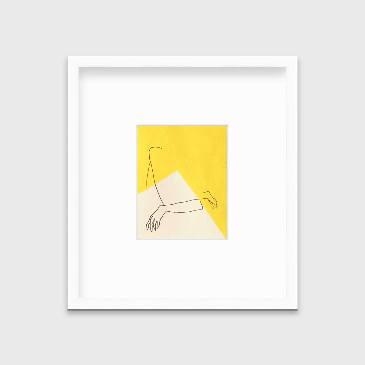 A yellow and white abstract print by Hazal Ozturk in a white frame with a mat hangs on a white wall.