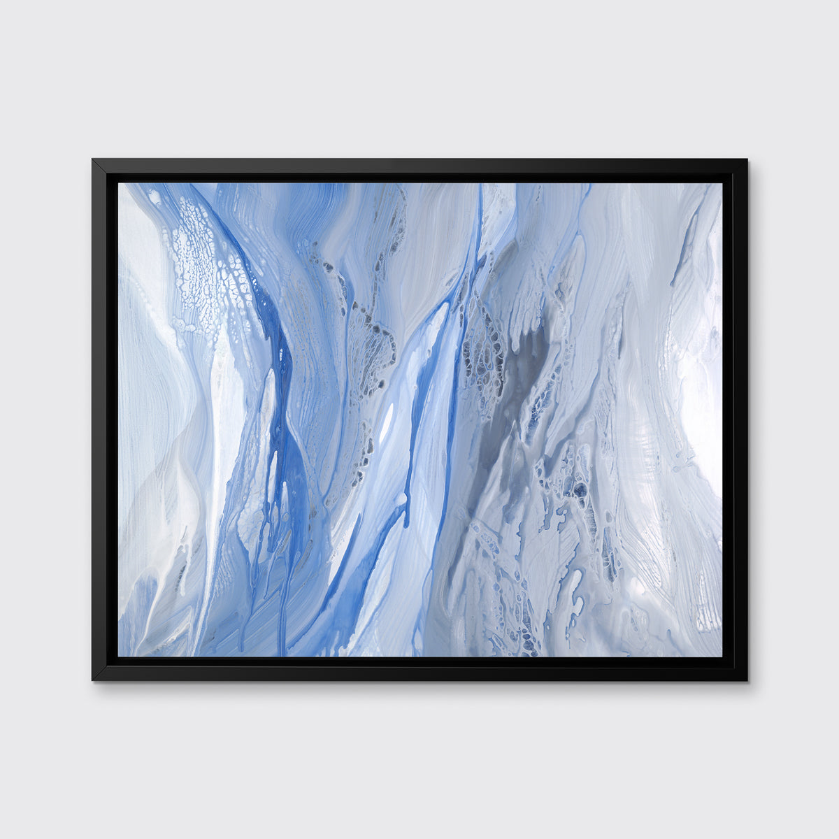 A blue, white and grey abstract print in a black floater frame hangs on a white wall.