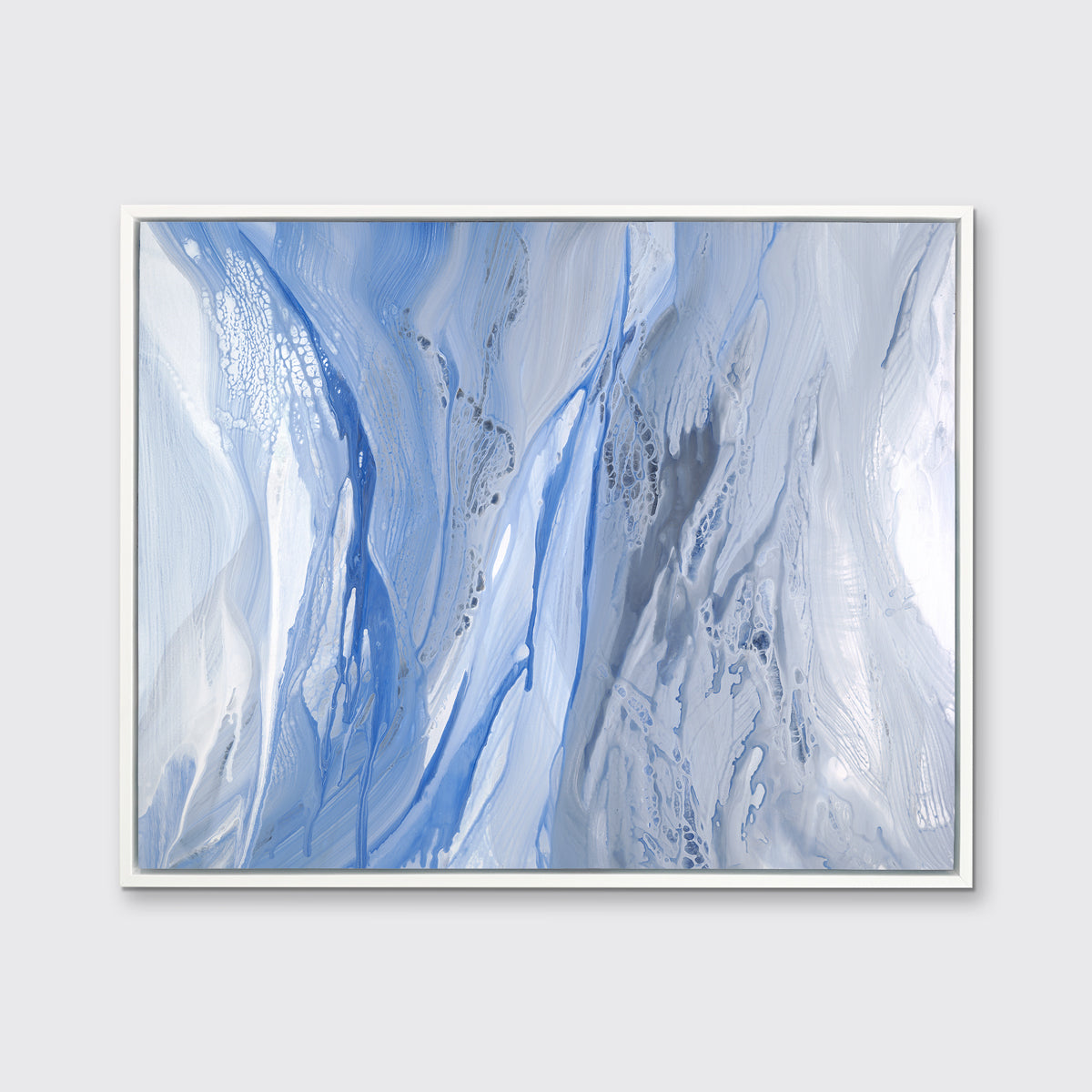 A blue, white and grey abstract print in a white floater frame hangs on a white wall.