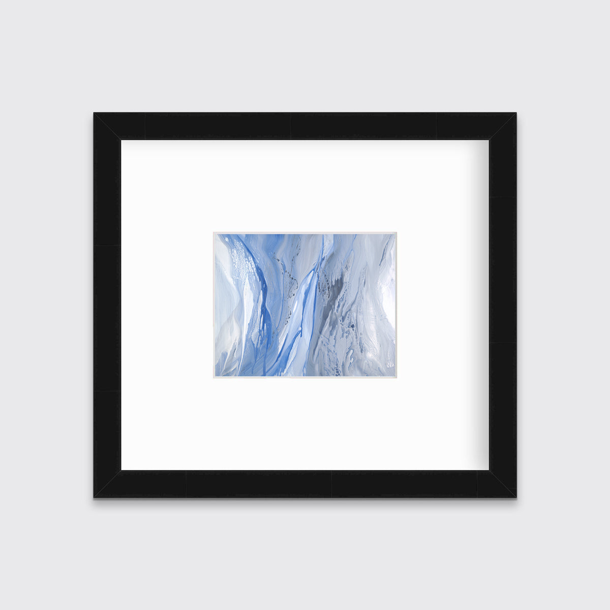 A blue, white and grey abstract print in a black frame with a mat hangs on a white wall.