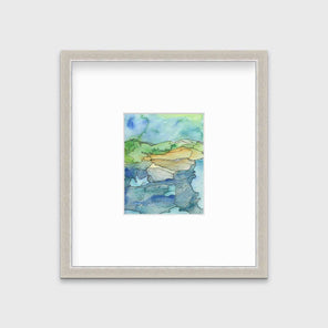 A blue and green landscape illustration in a silver frame with a mat hangs on a grey wall.