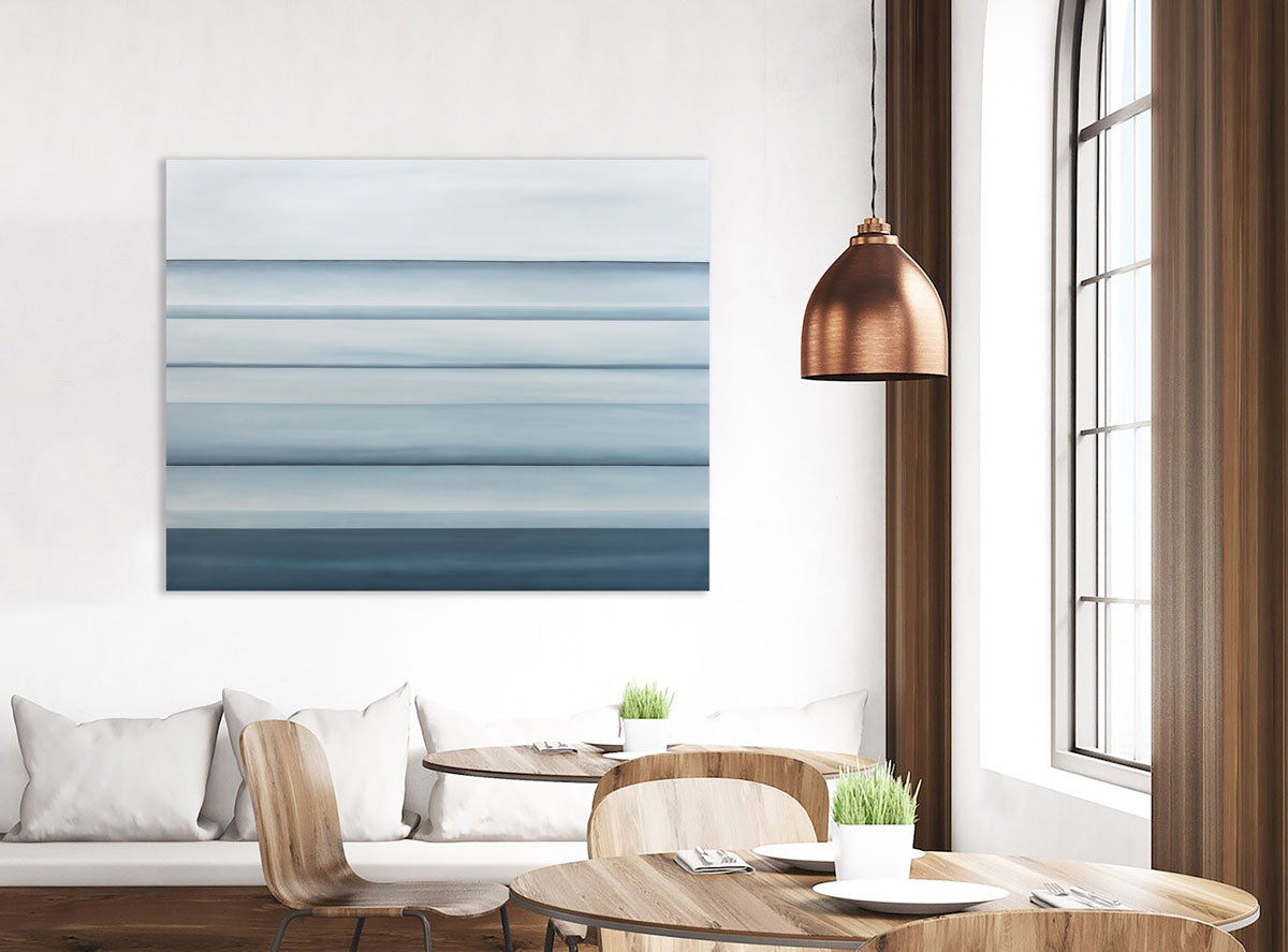 A blue oil painting with multiple navy lines running horizontally on the canvas which suggest horizon lines is hung in a cafe. Wired and ready to hang.
