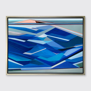 A tonal blue, green and beige geometric abstract landscape print in a silver floater frame hangs on a white wall.