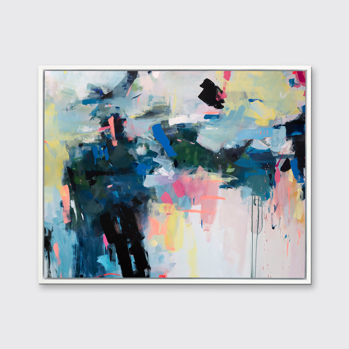 A multicolored abstract print in a white floater frame hangs on a white wall.