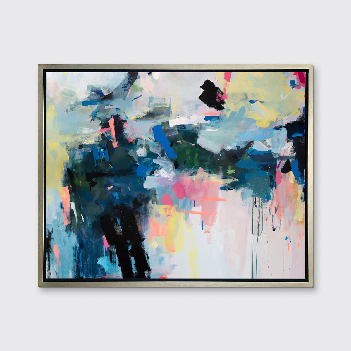 A multicolored abstract print in a silver floater frame hangs on a white wall.