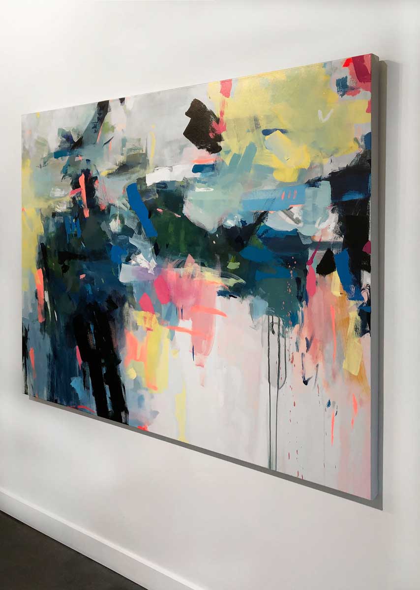 A right side-angle view of a colorful abstract painting by Kelly Rossetti hangs on a white wall.