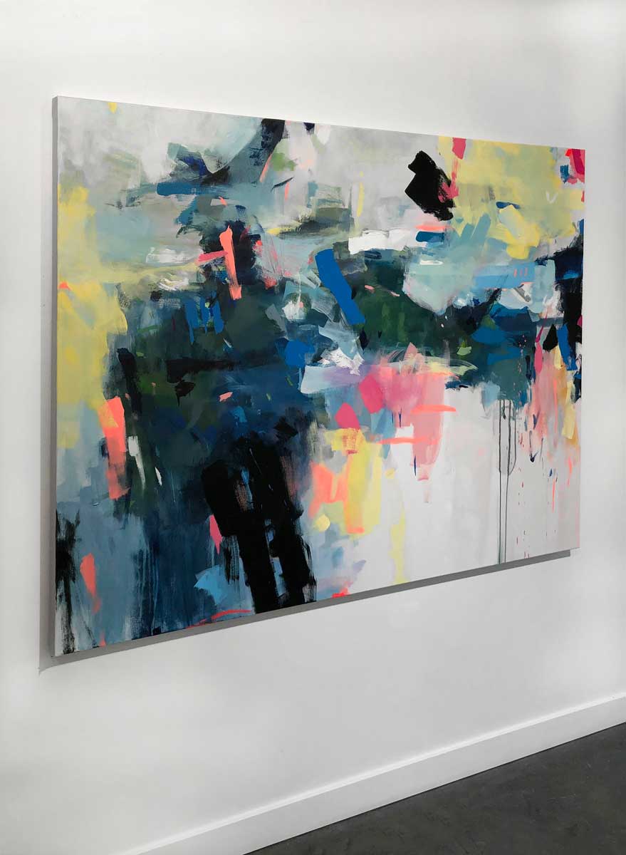 A left side-angle view of a colorful abstract painting by Kelly Rossetti hangs on a white wall.