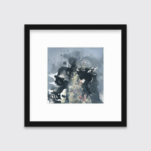 A grey, black, white and light yellow abstract print in a black frame with a mat hangs on a white wall.