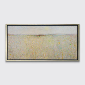 A white and yellow abstract landscape print in a silver floater frame hangs on a white wall.