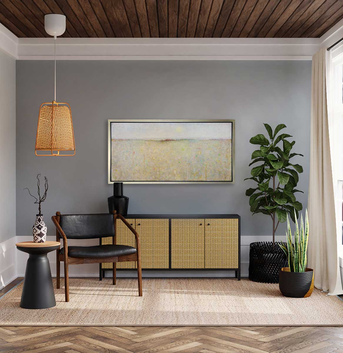A white and yellow abstract landscape print in a silver floater frame hangs on a grey wall above a black and rattan console table with a black vase, a black chair and two potted plants.