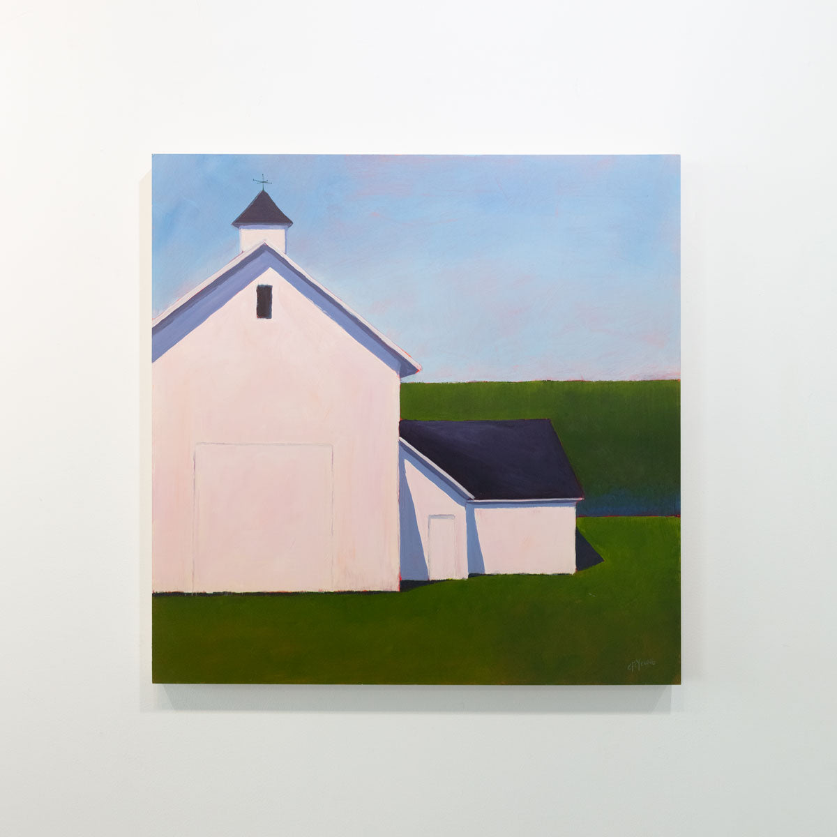 A painting of a white barn with a weather vane in front of a hedge is hung on a gallery wall.