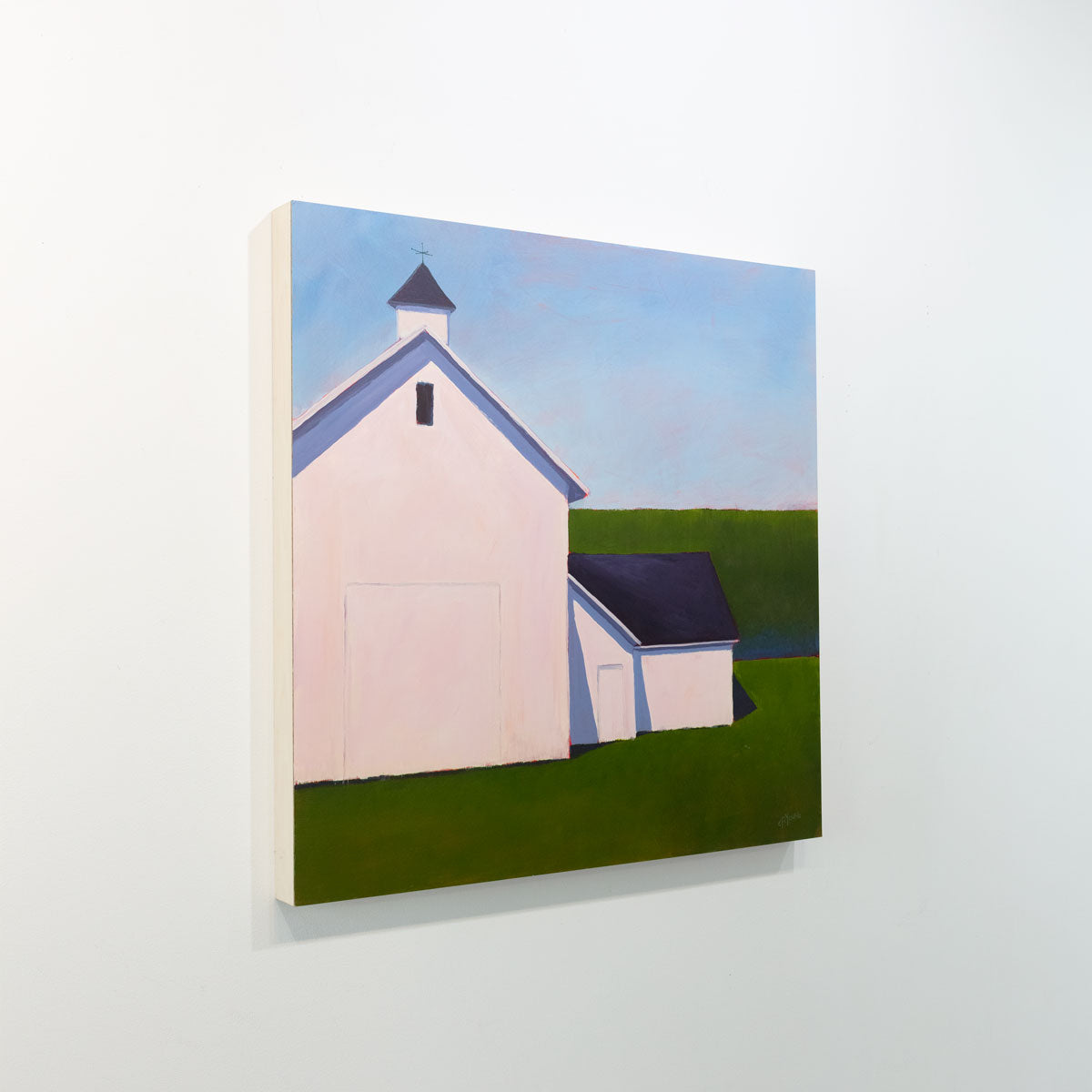 A painting of a white barn with a weather vane in front of a hedge is seen at an angle on a gallery wall.
