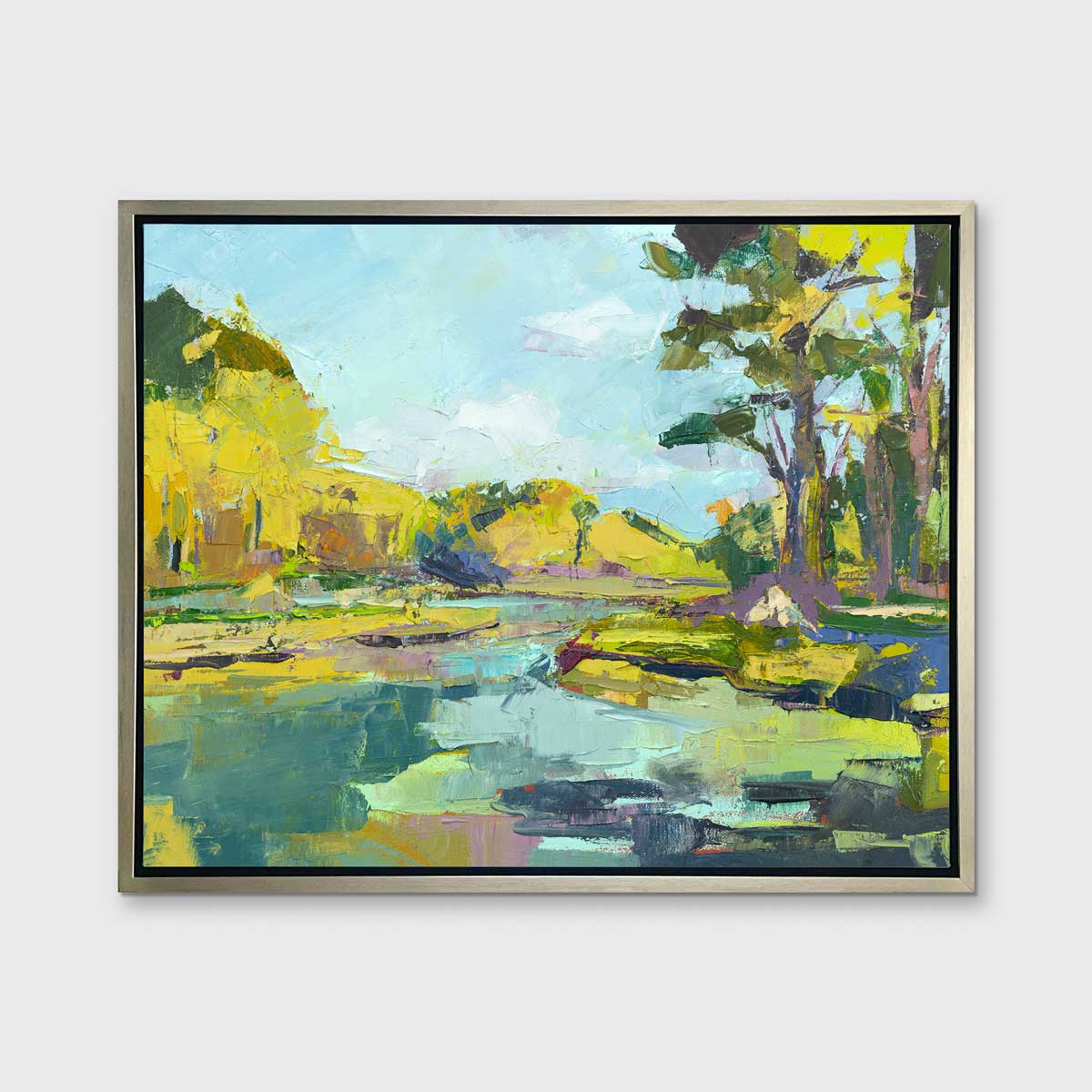 A chartreuse, light blue and green abstract landscape print in a silver floater frame hangs on a white wall.