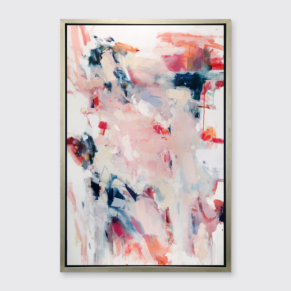 A pink, white and blue abstract print in a silver floater frame hangs on a white wall.