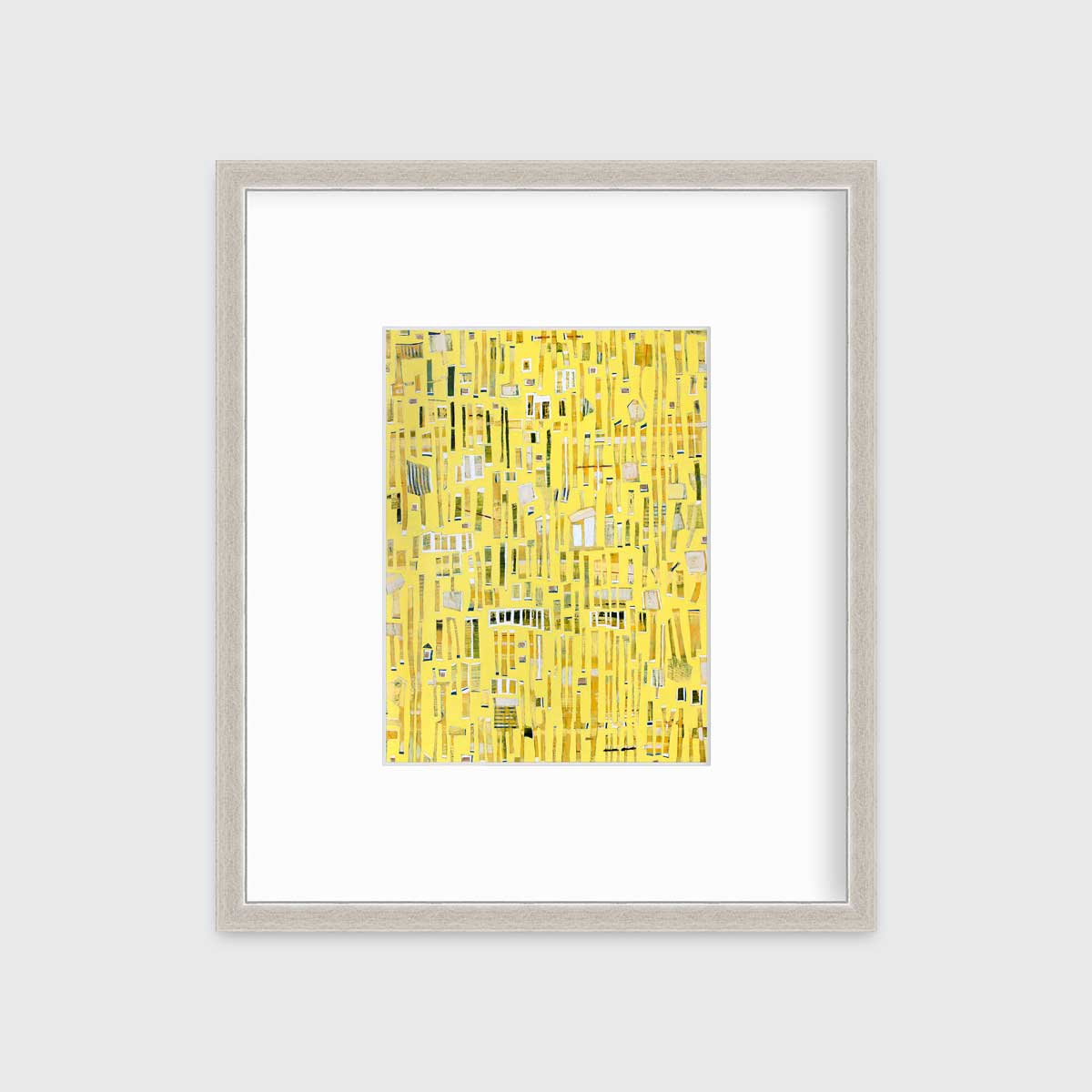 A yellow, white and black abstract print in a silver frame with a mat hangs on a white wall.