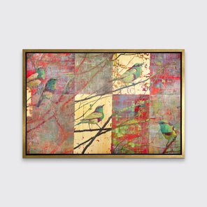 A red, gold and green geometric abstract print of birds in a tree in a gold floater frame hangs on a white wall.