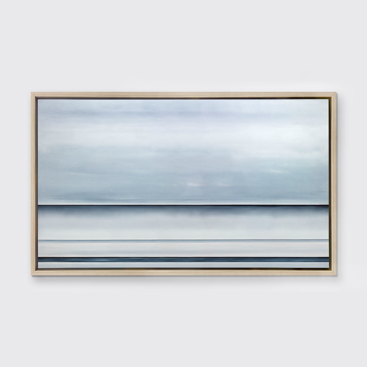A tonal blue abstract landscape print in a white oak wood floater frame hangs on a white wall.